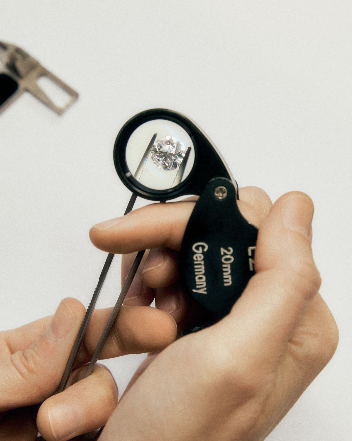 Hand holding loupe over diamonds